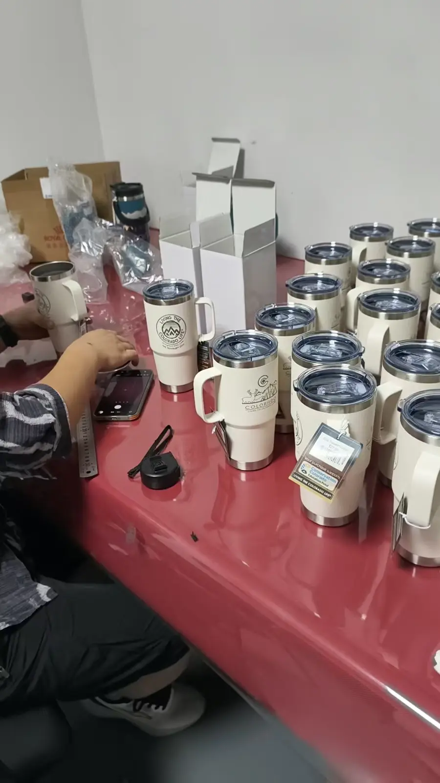 Inspector reviewing finished drinkware samples for appearance, applied logo and dimensions at a MOWXI-owned or affiliated factory site