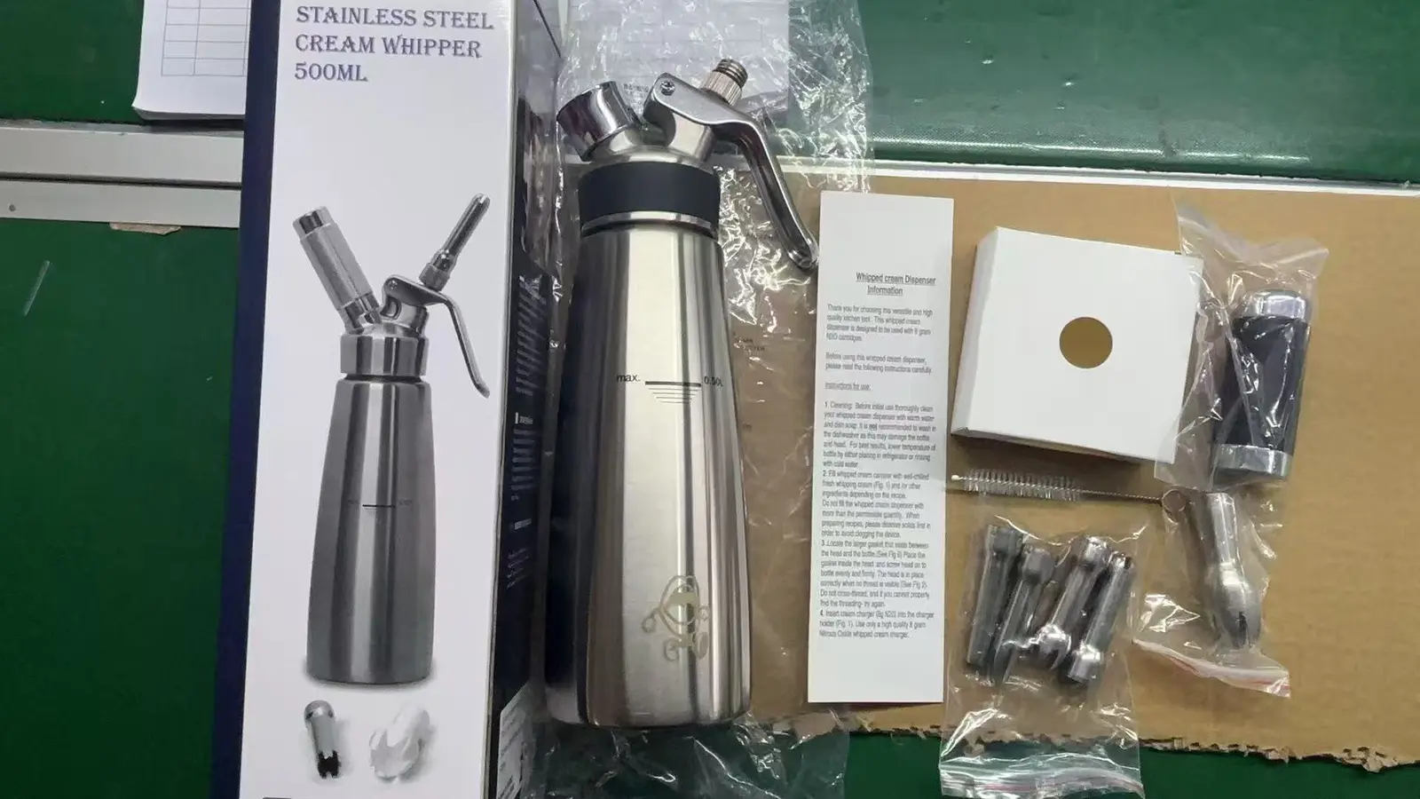 Stainless steel cream whipper with accessories, instruction leaflet and retail packaging prepared for buyer review