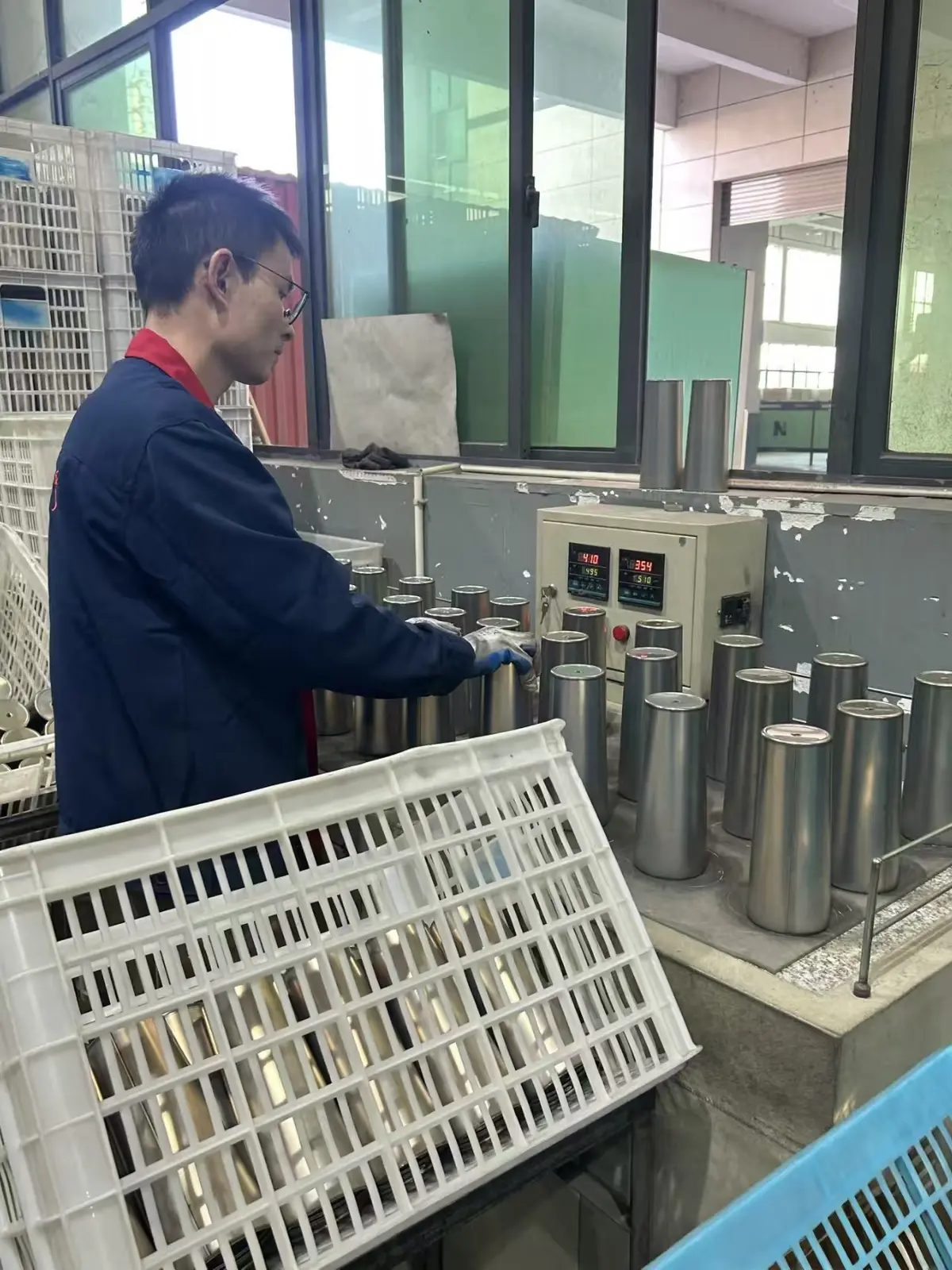Worker conducting thermal or vacuum performance testing on stainless steel drinkware bodies at a MOWXI-owned or affiliated factory site