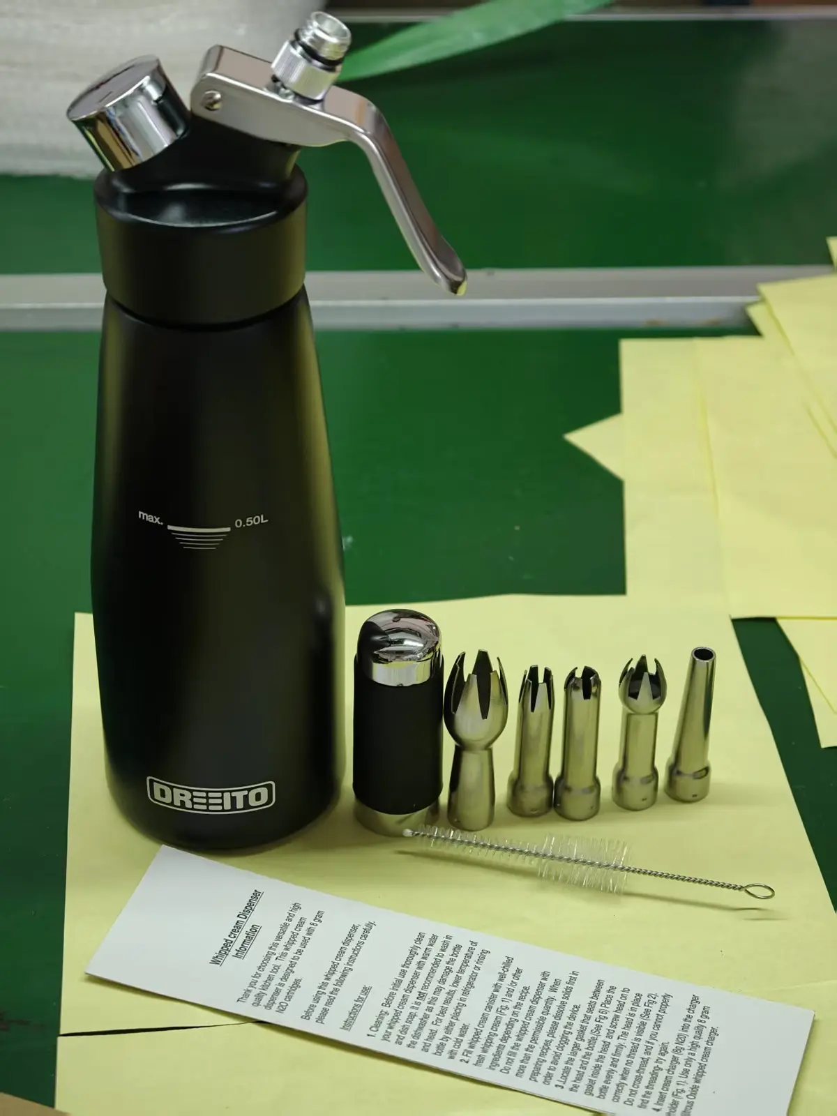 Black cream whipper with decorating tips, cleaning brush and instruction sheet, marked with a custom logo