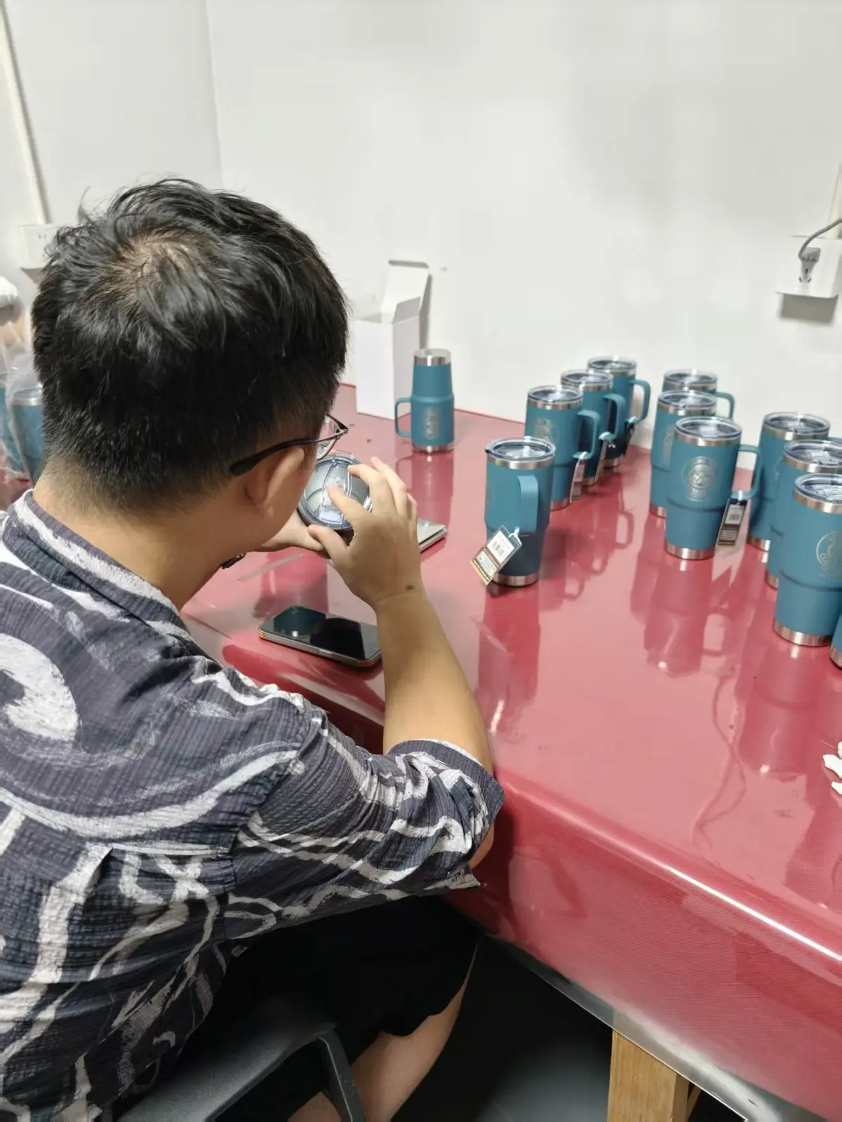 Inspector reviewing a drinkware lid, assembly and finished appearance at a MOWXI-owned or affiliated factory site